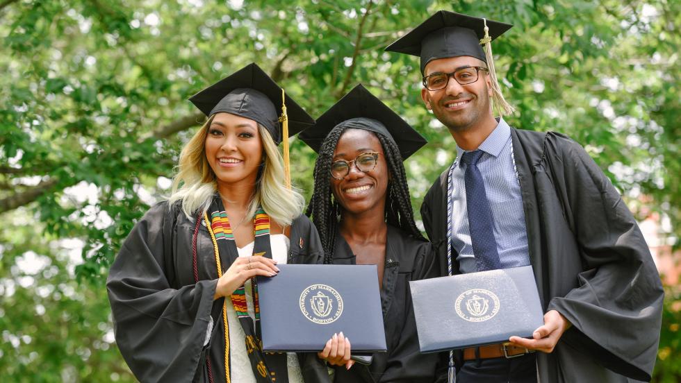 three graduates holding their diplomas
