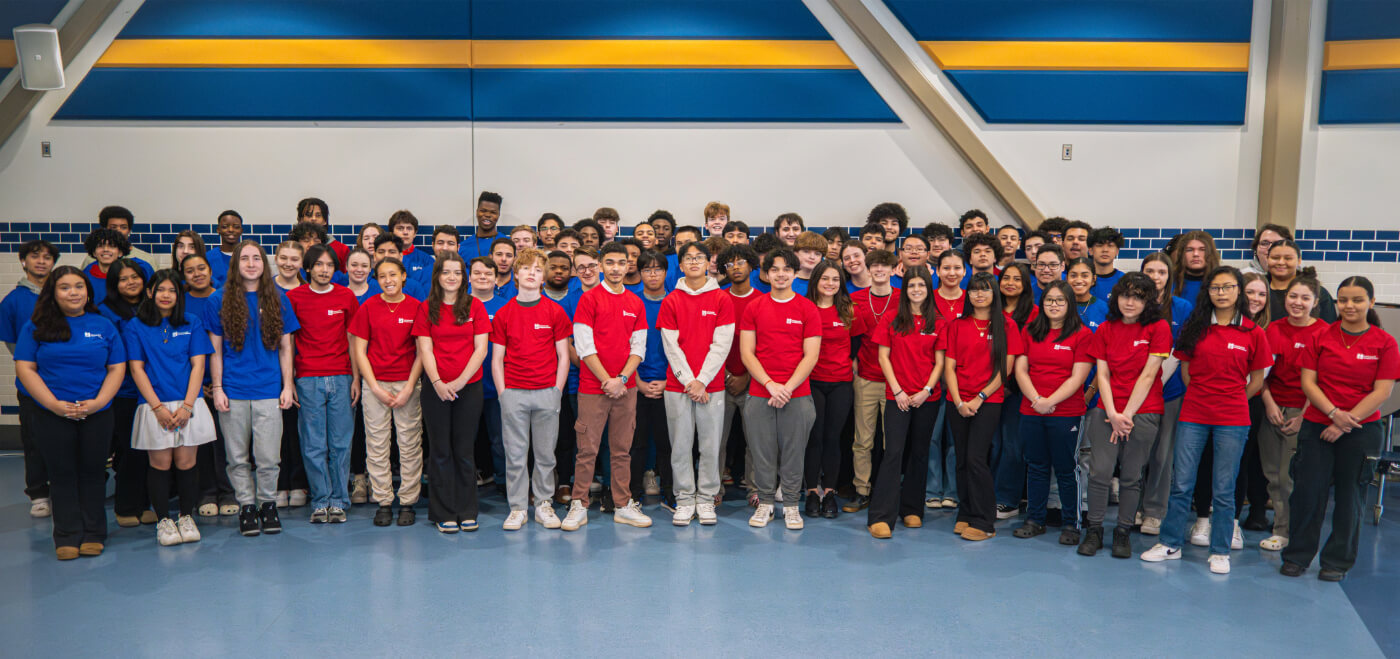 a large group of high school-aged teenagers posing in red and blue matching t-shirts